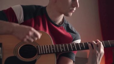 Mutlu genç adam akustik gitar çalar.