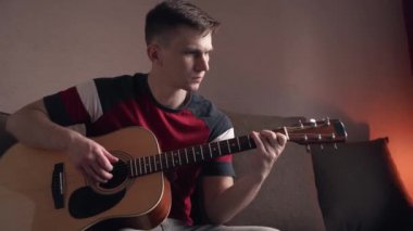 Genç adam akustik gitar çalmayı öğreniyor. çevrimiçi öğrenme.