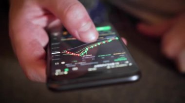 İşadamı, cep telefonu ekranındaki dijital bir değiş tokuşun fiyat tablosunu kontrol ediyor. yakın plan.