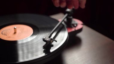 Adam vinil çalar çalıştırıyor. Karanlık bir oda. yakın plan.
