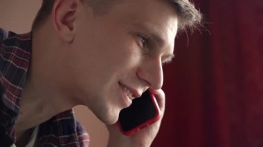 Gülümseyen genç adam cep telefonuyla konuşuyor..