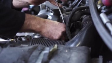 Genç oto tamircisi bir araba motorunu tamir eder. buji değişimi.