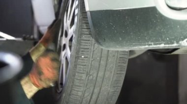 Genç oto tamircisi arabaya tekerlek takıyor. oto tamirhanesi.