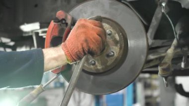 Genç oto tamircisi eski bir arabayı tamir eder. tekerlek taşıyıcı kurulumu.