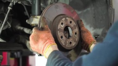 Genç oto tamircisi eski bir arabayı tamir eder. fren diski kurulumu.