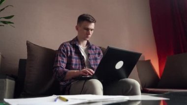 Genç adam evde bilgisayar kullanarak uzaktan öğrenme yapıyor. Koronavirüs izolasyonu.