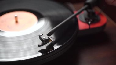 Vinil plak çalar. Tahta bir masada..