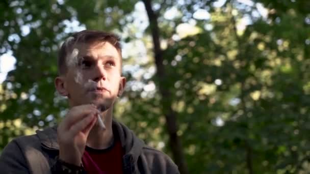 Junger Mann Raucht Einem Stadtpark Eine Zigarette Porträt Nahaufnahme — Stockvideo