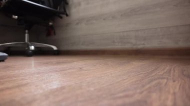 Adam odayı elektrikli süpürgeyle temizliyor. Yakın plan. parke.