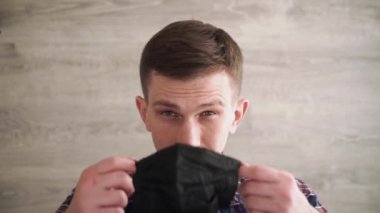 Kafkas adam kameraya bakarak tıbbi koruyucu siyah yüz maskesi takıyor. Tarafsız bir arkaplanda portre. Koronavirüs önleme.