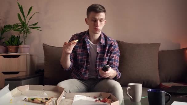 Gelukkige Jongeman Die Pizza Eet Terwijl Hij Thuis Zit Kijken — Stockvideo
