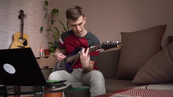 年轻人在家里学习在网上弹奏电吉他 — 图库视频影像