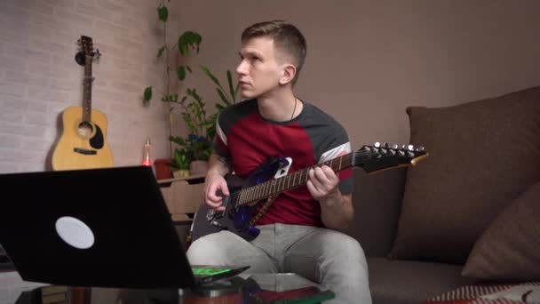年轻人在家里学习在网上弹奏电吉他 — 图库视频影像