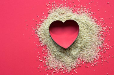 Kalp şeklinde serpilmiş kuskus Groats aşk rengi bir arka planda yatıyordu. Metin alanı olan Sevgililer Günü fikri.