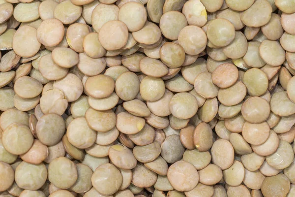 Sağlam ve yassı yeşil mercimek tohumları yığını. En eski gıda mahsulü. Sağlıklı besin arkaplanı.