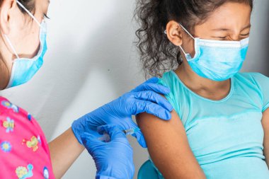 Çocukların hemşiresi kahverengi kızın koluna enjekte ediyor. Evden eve aşılama planı, doktorun elinde lastik eldivenler, kovid 19 aşısı. Grip aşısı. tıbbi konsept, sağlık ve salgın hastalık.