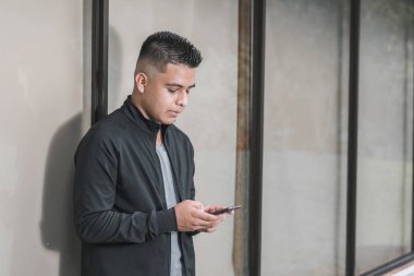 Cep telefonundaki sosyal ağlara bakan genç girişimci, camdan pencereye yaslanmış, cep telefonu ile internetten alışveriş yapan öğrenci ya da nüfuzlu biri. teknolojik kavram