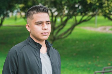 Kısa saçlı, siyah giyinmiş, parkta yürüyüş yapan, yeşil parkta yürürken geleceğini analiz eden düşünceli bir çocuk. Özgürlük kavramı