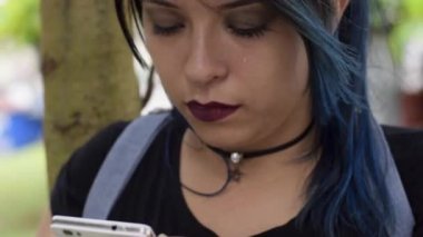 Gözyaşı dökerken cep telefonuna bakıp gülümseyen genç Latin kadının yakın çekimi. Hüzünlü kadın, kısa mesajla kötü haber alıyor. Üzüntü ve mutluluk kavramı