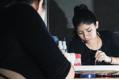 Aynanın önündeki güzel Latin kadın gözlerini boyuyor. Elinde makyaj fırçasıyla renkli gölgeler paletinden makyaj tozu alan bir kız. güzellik, kozmetik ve el işi konsepti.