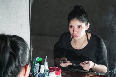 Aynanın önündeki güzel Latin kadın, bakışlarını yeni yaptığı gözlerine dikmiş, makyajının iyi olup olmadığını ciddi bir bakışla gözlemliyor. Güzellik ve kozmetik kavramı.