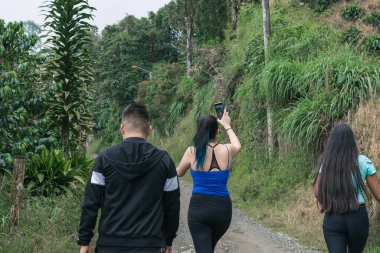 Pereira-Kolombiya yakınlarındaki kahve bölgesinde yürüyüş yapan üç genç Latin, sosyal ağları için içerik kaydeden genç doğa yürüyüşçüleri.