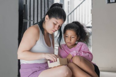 Anne ve kızı, yurtdışında yaşayan kocası tarafından kendisine gönderilen kutuya bakıyor. Üzgün kız çünkü babası uzakta ve onu ziyarete gelemiyor. Terk edilme kavramı.