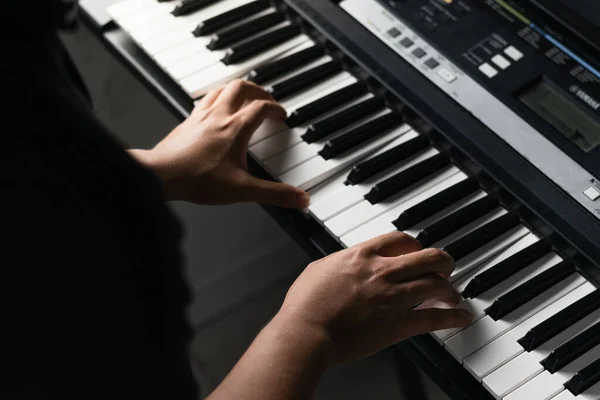detail shot of a young latino boy's hands practicing and playing synthesizer, for his piano high and low notes exam. top view of a boy practicing his hobby. online music production classes