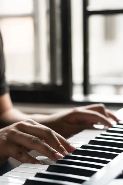 detail shot of a boy learning to play piano at home. hands of a latin man practicing his hobby, creating new musical works and melodies for his compositions.