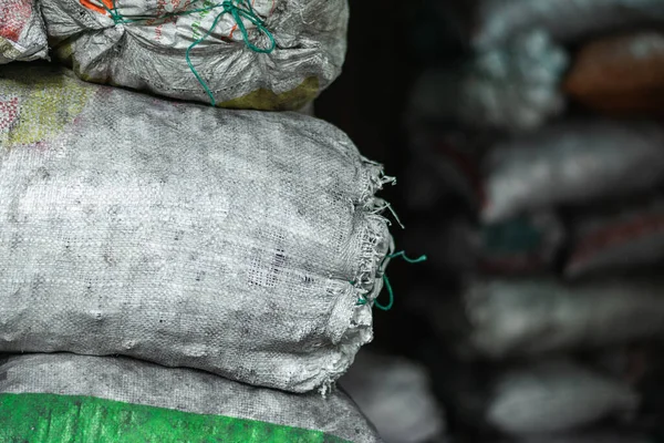 detailed view of white sacks filled with material and products inside a dark warehouse. sacks filled with charcoal ready to be processed and sold in the colombian market. industry concept