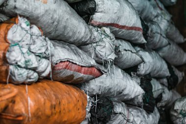 white and orange sacks filled with material and products inside a warehouse. sacks filled with charcoal ready to be processed and sold in the colombian market. sale of material for food processing.