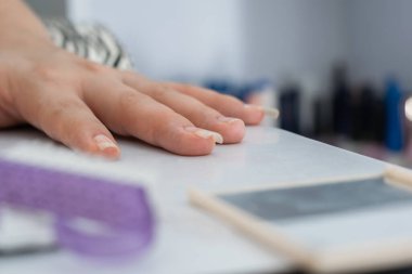 close-up of matte black nail polish on a white manicure table, in the background a hand with black painted nails. concept of beauty and dark style.