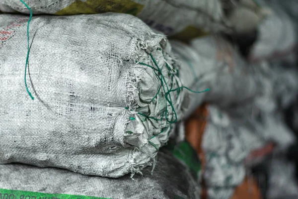 detailed view of white sacks full of material and products inside a warehouse, tied with green ribbons or cabuyas. sacks full of charcoal ready to be processed and sold in the Colombian market.