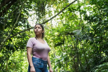 Kolombiya ormanının ortasında gezen güzel bir Latin kız. Kadın, Güney Amerika ormanlarının güzel doğasında yürürken merakla bakıyor..