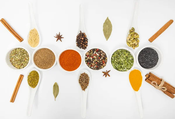 Seasonings for food. Set of different culinary spices in white ceramic bowls and spoons, on a white background