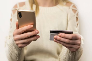 Para transferi çevrimiçi ödeme. Kadın internet mağazasından alışveriş yapıyor, el ele tutuşuyor ve kredi kartını alışveriş için akıllı telefonunu kullanıyor.