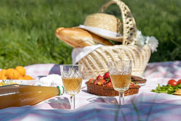 Picnic in the park, white wine in glasses, and baguettes in a basket