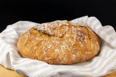 Ev yapımı ekmek. Ahşap bir zeminde taze pişmiş yuvarlak ekmek, açık renkli bir havlu giy.