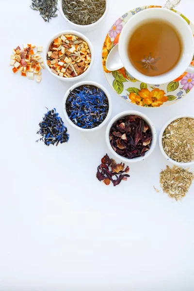 A cup of tea. Variety of dry tea in utensils, on a white background, place for text.
