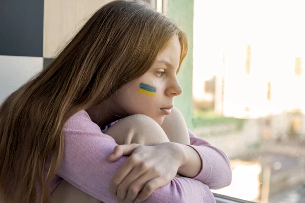 우크라이나 국기를 그을린 우크라이나 소녀가 창밖을 내다보며 나기를 기다립니다 러시아 — 스톡 사진