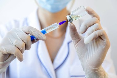 Aile hekimi. Doktor elinde şırınga ve şırınga ile aşı için bir şişe tutuyor. Tedavi konsepti, iğneler, aşılar ve klinik deneyler. Kapat.