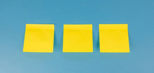 Three Yellow Blank Square Stickers Blue Background Copy Space Reminder — Zdjęcie stockowe