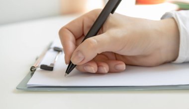 Make a note, female hand holding a pen, ready to write something on a blank sheet of paper, white sheet