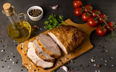 Kesme tahtasında pişmiş et. Arka planda vişneli domates ve zeytinyağı var.