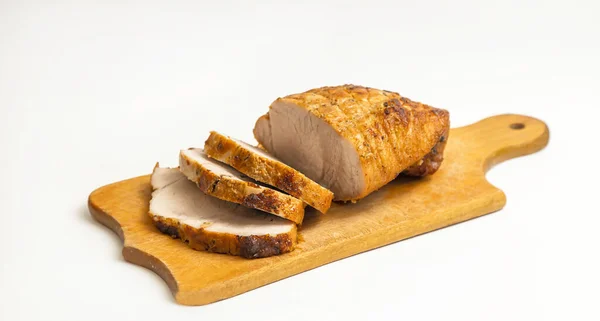 Homemade baked pork tenderloin with spices on a wooden kitchen board, on a white background.