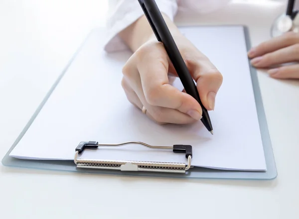 A medical worker records the history of a sick patient. Clipboard closeup