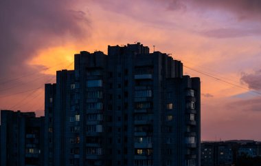 Brick high-rise in the rays of the setting sun and red fiery sky
