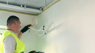 A young male master painter paints the walls by hand with a roller during interior renovation work