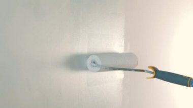 Apartmanda tamirat var. Bir işçi duvarları silindirle boyar.