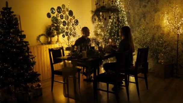 Sevgi dolu evli bir çiftin silueti Noel arifesinde yemek yiyor, hediyelerini veriyor ve şampanya içiyor. — Stok video